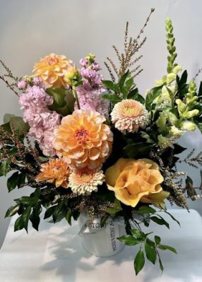 A florist in Chirn Park wraps a pastel bouquet by hand, laptop open beside her with Moss n Stone’s Order Flowers Online page on display. Fresh roses and lilies scatter the table, sunlight streaming in.